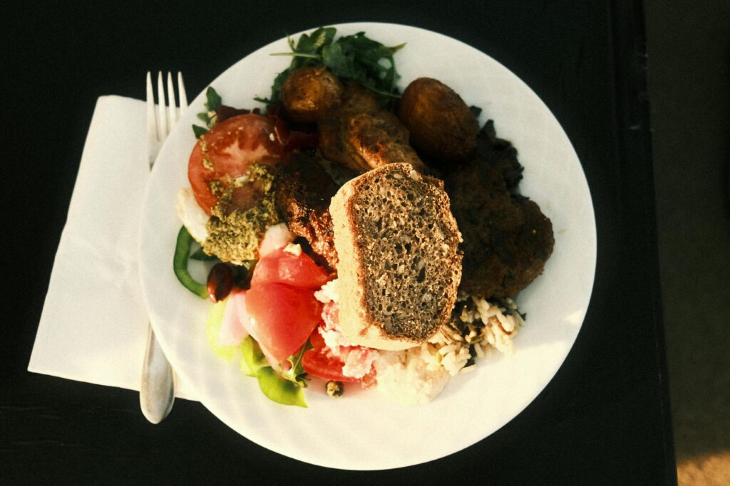 A close-up of a colorful Mediterranean meal with bread and vegetables, captured from above.