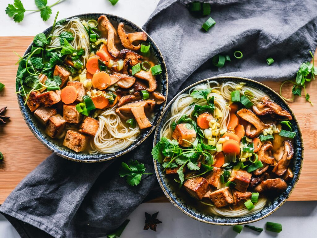 A vibrant noodle bowl with tofu, mushrooms, and fresh vegetables, perfect for a healthy meal.